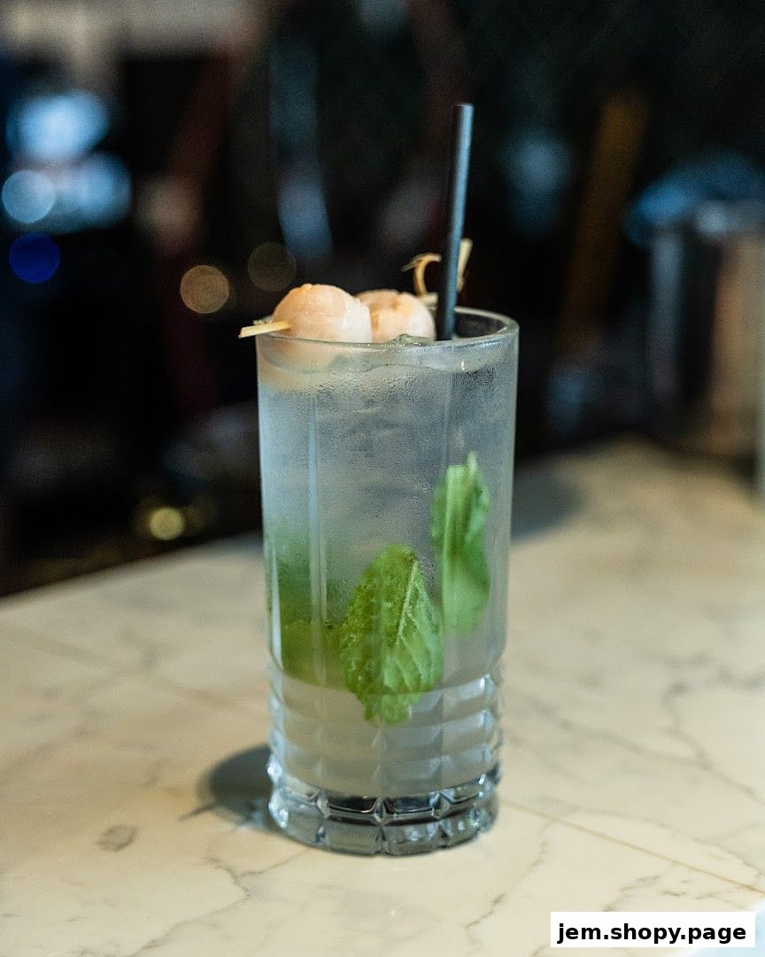 A refreshing cocktail with lychee and mint served in a tall glass.