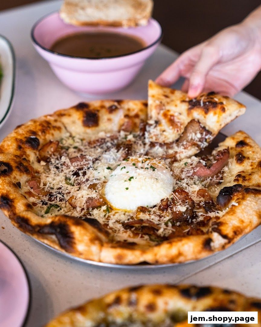 A hand reaches for a slice of pizza topped with cheese, bacon, and a poached egg.