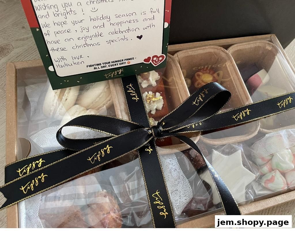 A gift box filled with assorted festive treats, tied with a branded ribbon.