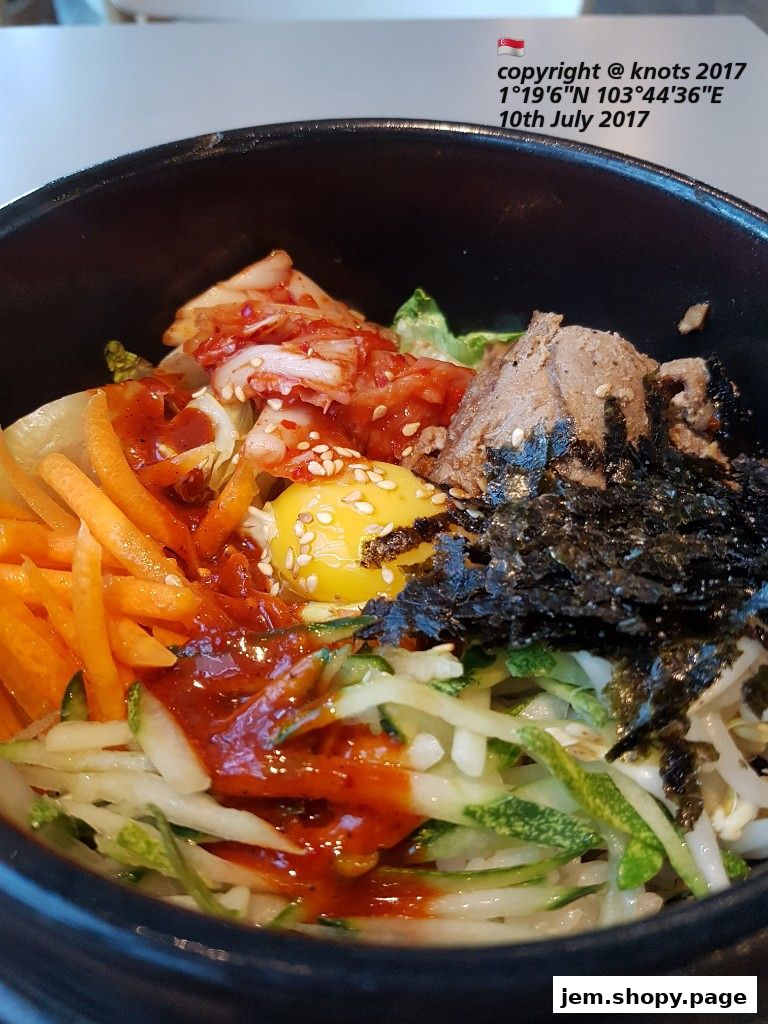 A close-up shot of a delicious Korean bibimbap served in a black bowl.