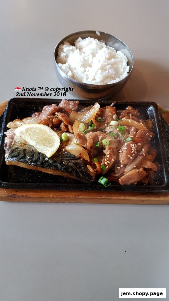 A sizzling plate of Korean food with grilled fish, meat, and a side of rice.