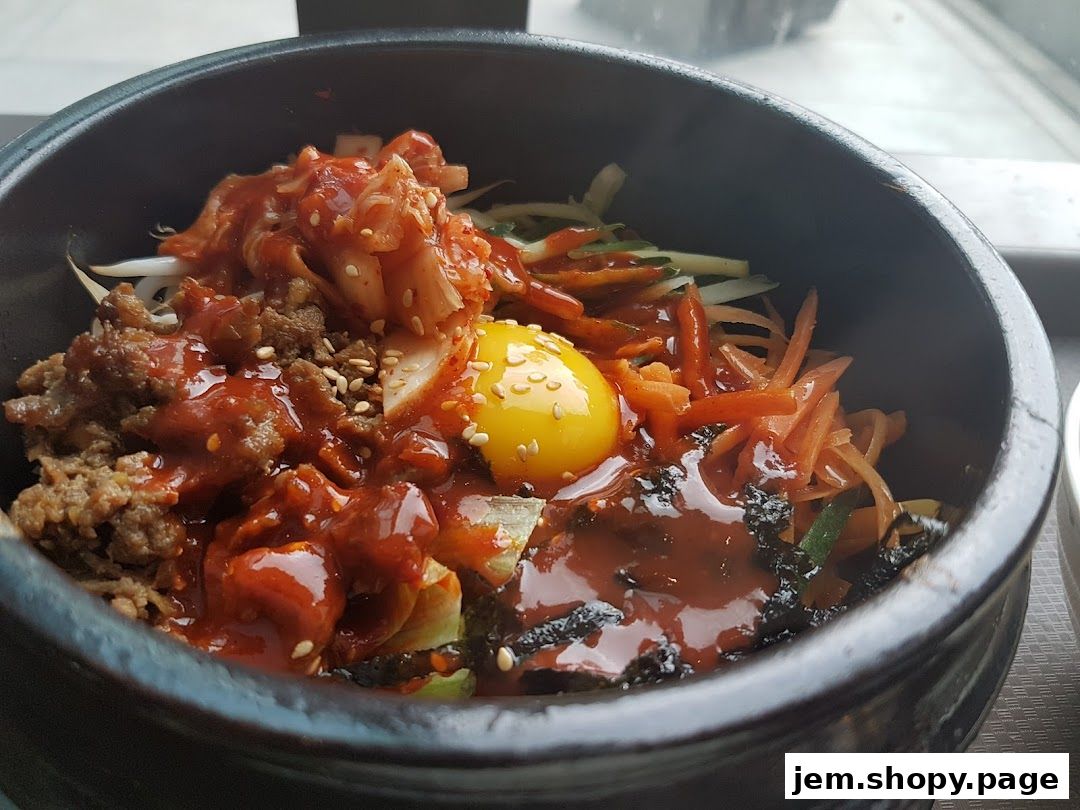 A close-up of a delicious Korean bibimbap served in a stone bowl with a raw egg yolk.