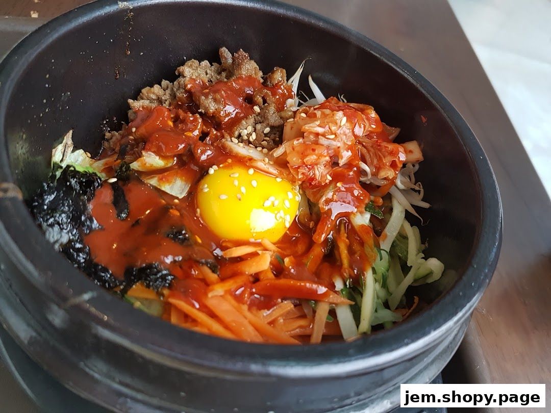 A close-up of a delicious Korean bibimbap served in a stone bowl with a raw egg yolk.