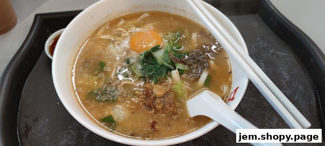 A close-up of a steaming bowl of Korean noodle soup with an egg yolk and vegetables.