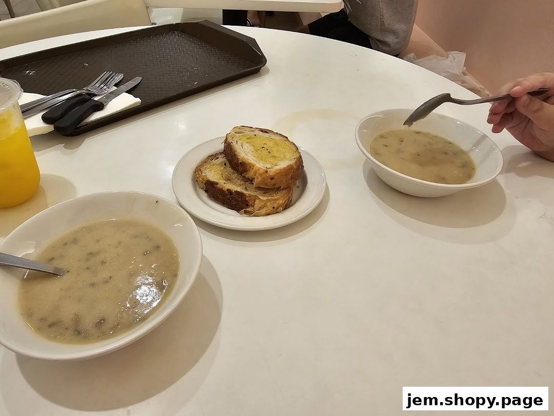Two bowls of soup and toasted bread served on a white table.