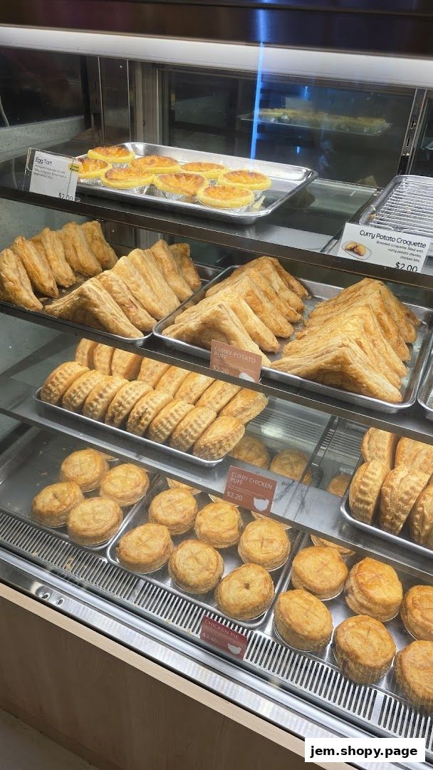 A display case filled with various baked goods including tarts, puffs, and pies.