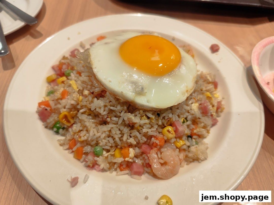 A plate of fried rice topped with a sunny-side-up egg and garnished with shrimp and vegetables.