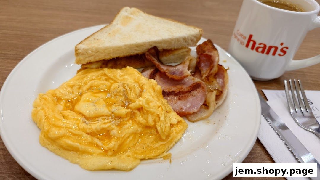 A plate of scrambled eggs, bacon, and toast with a cup of coffee from Hans Union.