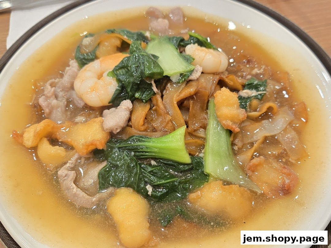 A close-up of a delicious noodle dish with shrimp, pork, and vegetables in a savory sauce.