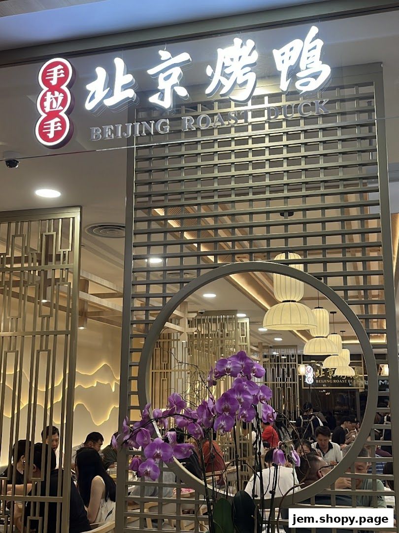 The entrance of Hand in Hand Peking Duck restaurant with elegant decor and diners inside.