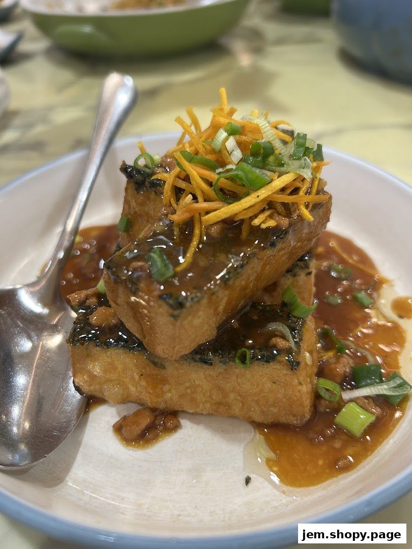 Crispy fried tofu cubes topped with shredded vegetables and scallions in a savory sauce.