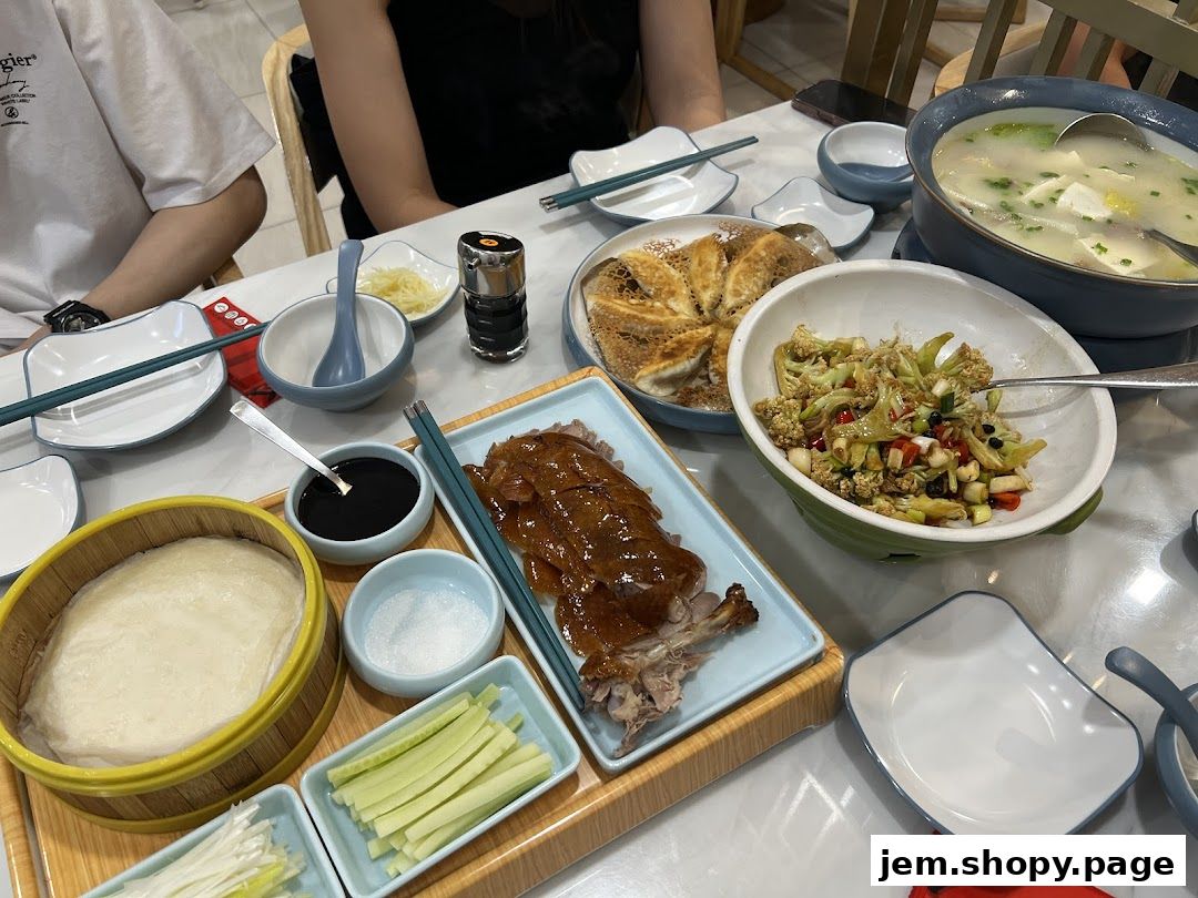 A table laden with Peking duck, dumplings, soup, and side dishes, ready for a meal.