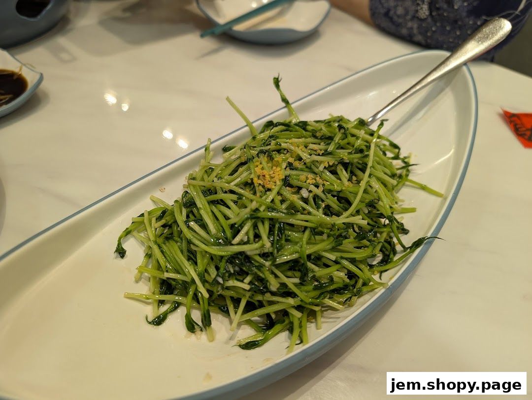A close-up of a fresh, green vegetable dish served in an elegant white oval platter.