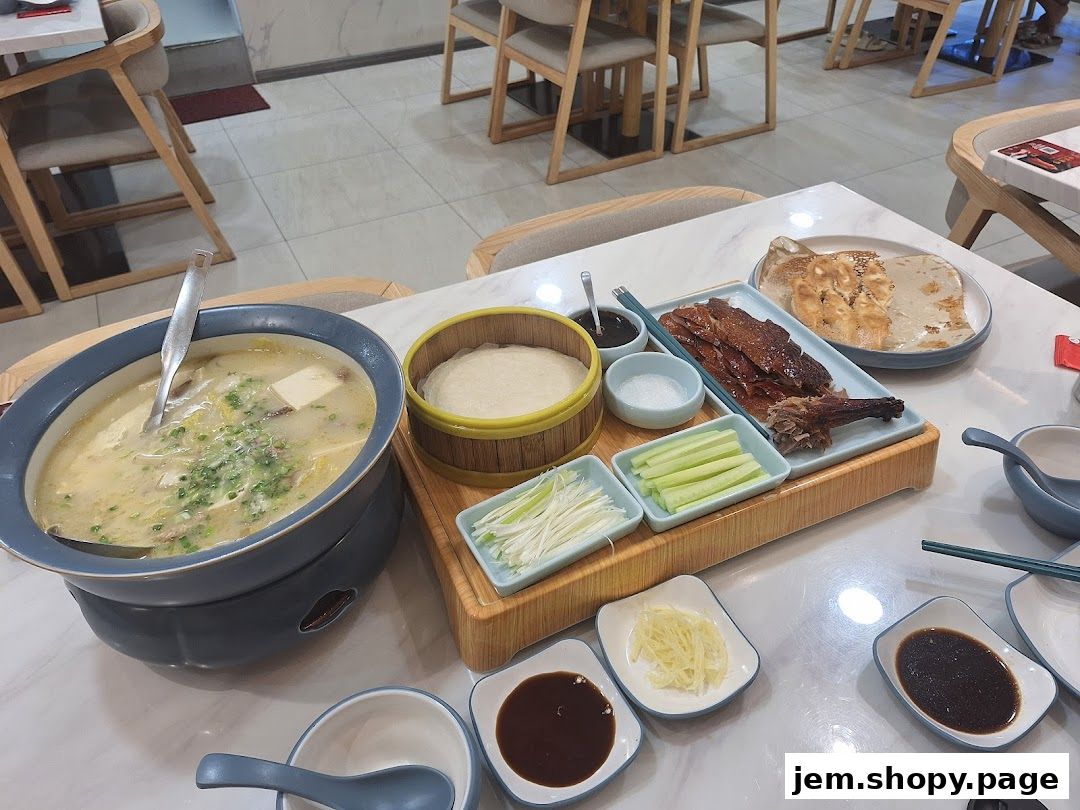 A table set with Peking duck, soup, pancakes, and various condiments.