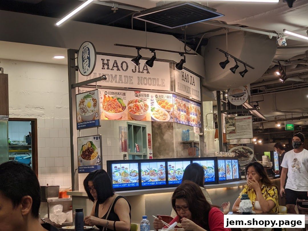 A food stall called Hao Jia Handmade Noodle with displayed menu items and customers.
