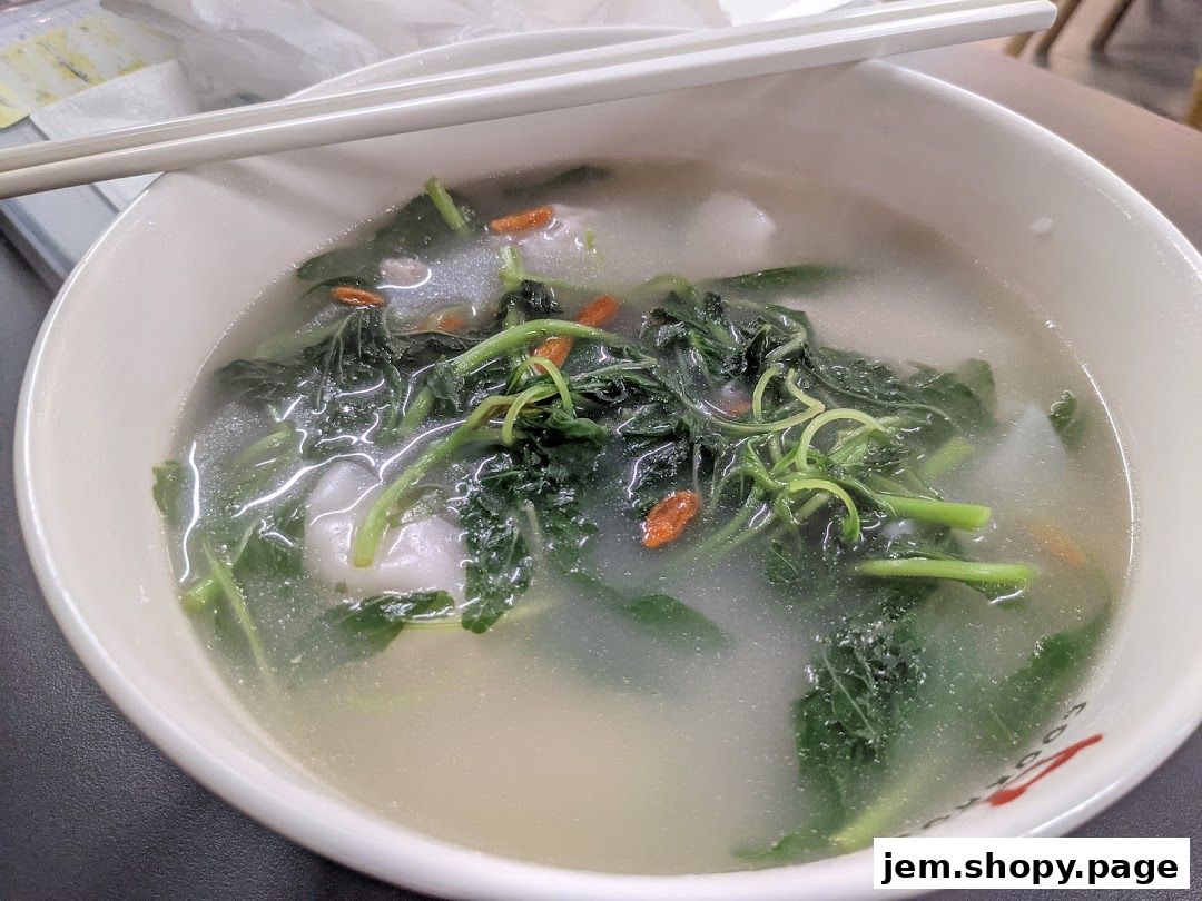 A close-up of a steaming bowl of handmade noodles with fresh greens and goji berries.