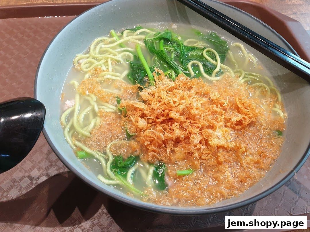 A close-up shot of a delicious bowl of handmade noodles with crispy toppings and greens.