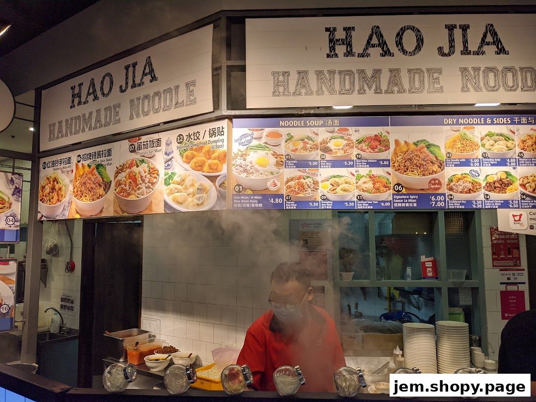 A food stall menu displaying various noodle dishes and dumplings with prices.