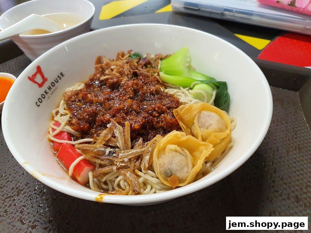 A bowl of delicious handmade noodles with toppings and a side of soup.