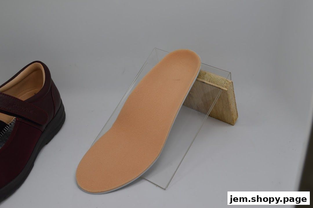 A burgundy shoe and an orthopedic insole are displayed on a white surface.