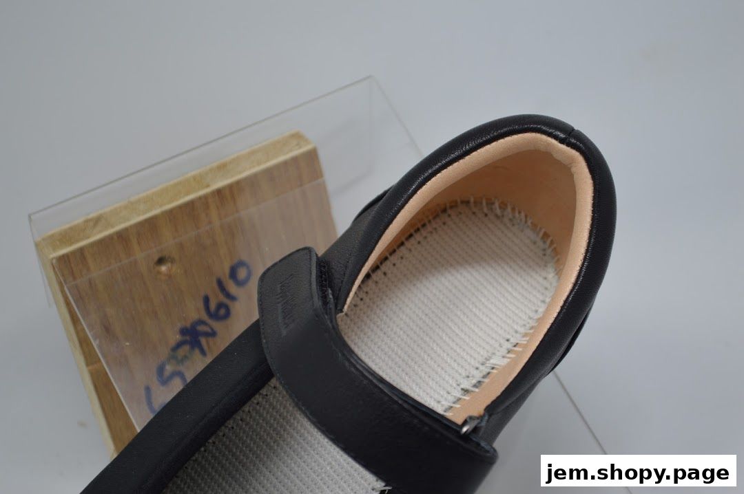 Close-up of a black shoe with a velcro strap, showcasing its interior.