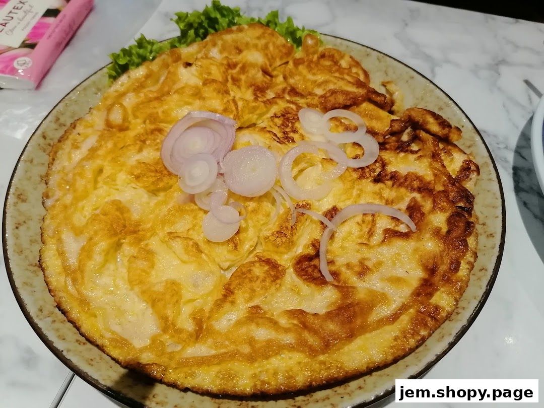A golden-brown omelet topped with sliced red onions and lettuce on a plate.