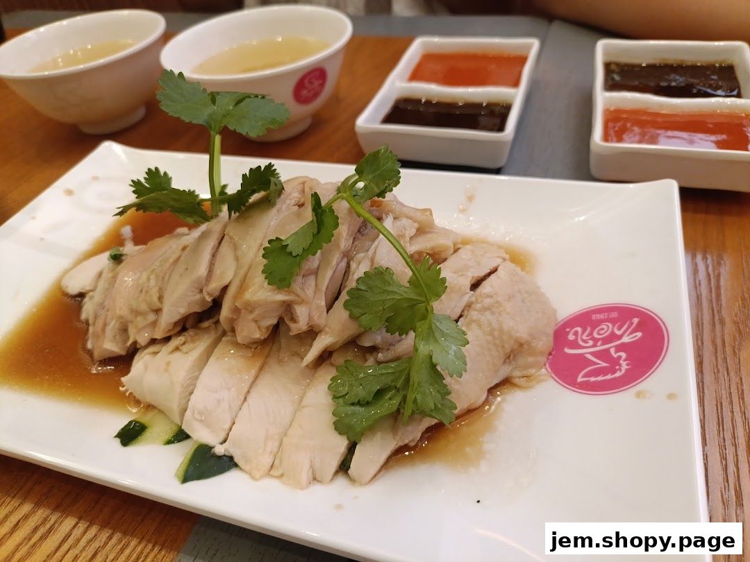 A plate of sliced poached chicken with dipping sauces and soup.
