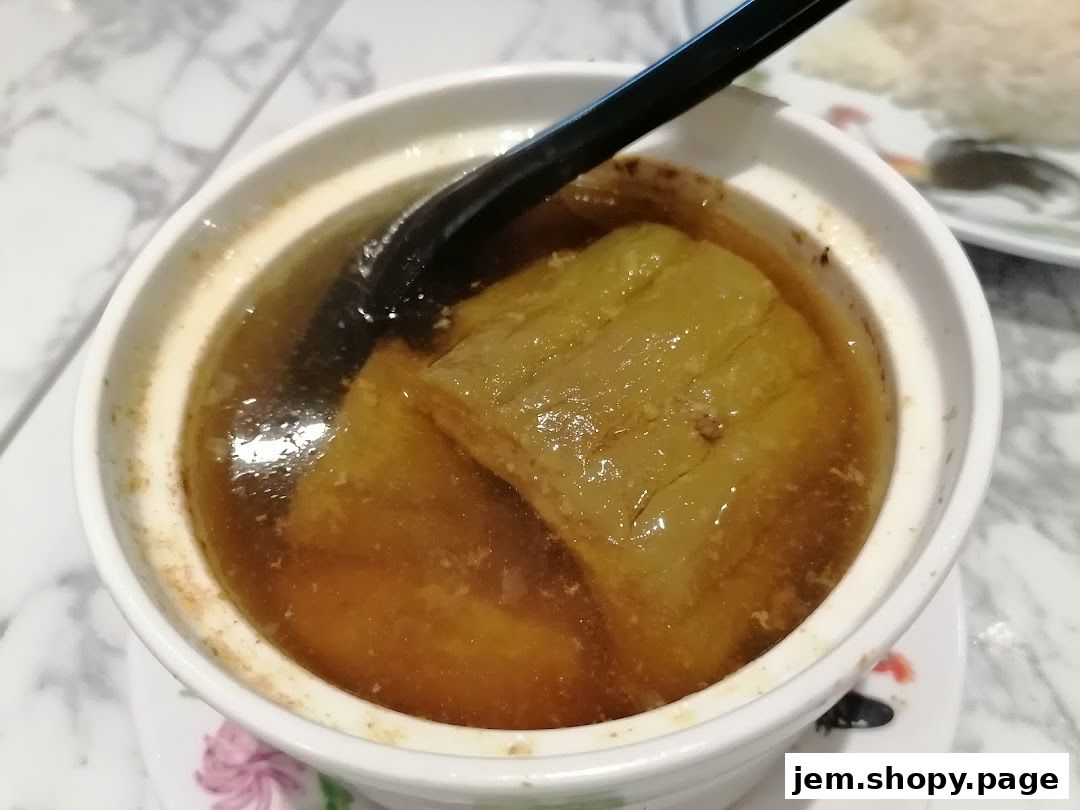 A close-up shot of a bowl of soup with large pieces of food and a spoon.