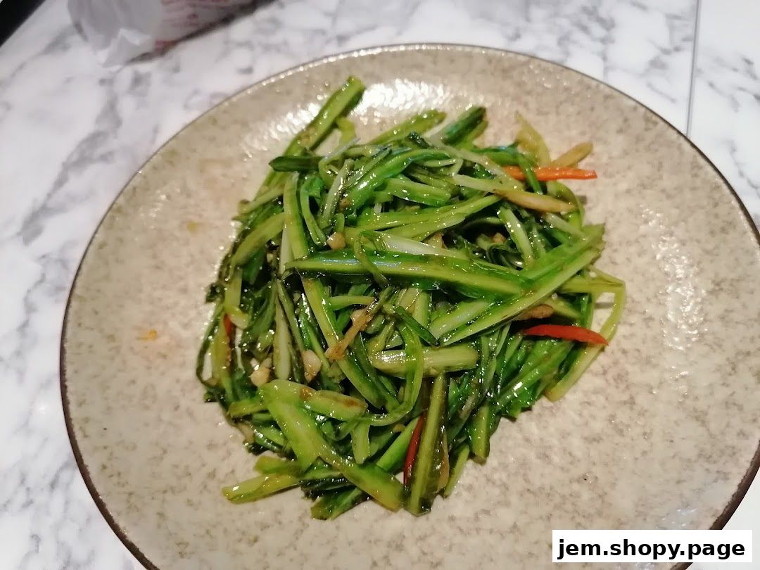 A plate of stir-fried shredded cucumber with chili and garlic on a marble table.