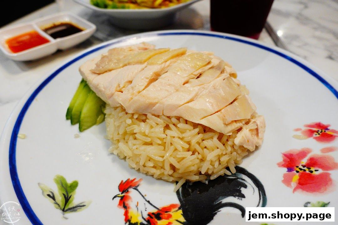 A plate of Hainanese chicken rice with sliced chicken and rice, served with dipping sauces.