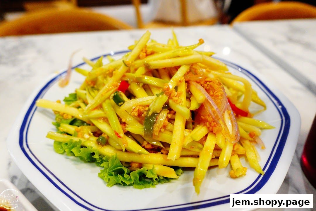 A plate of shredded green mango salad with chili, onions, and peanuts.