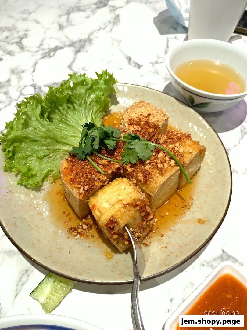 A plate of fried tofu with lettuce, cilantro, and a side of sauce and soup.