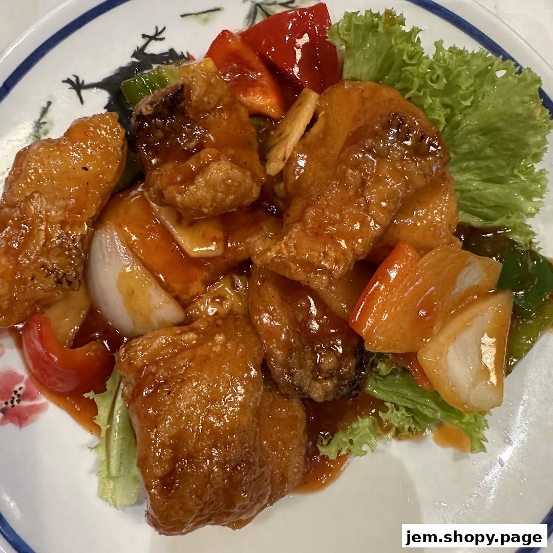 A plate of sweet and sour fish with vegetables and lettuce garnish.