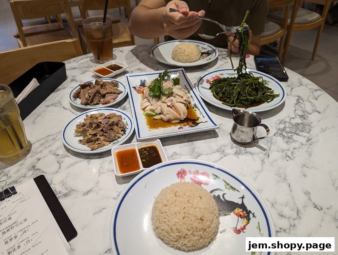 A table laden with delicious Hainanese chicken rice and stir-fried vegetables.