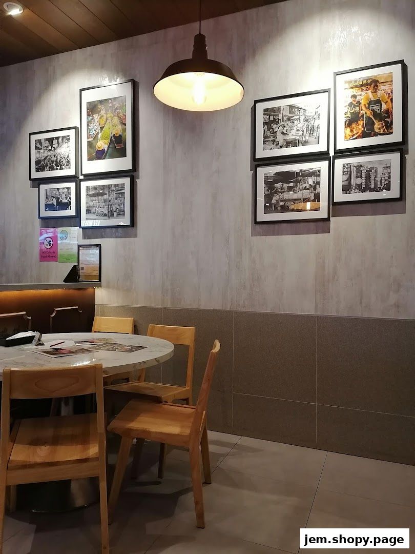 Interior shot of a restaurant with framed photos on the wall and wooden chairs around a table.