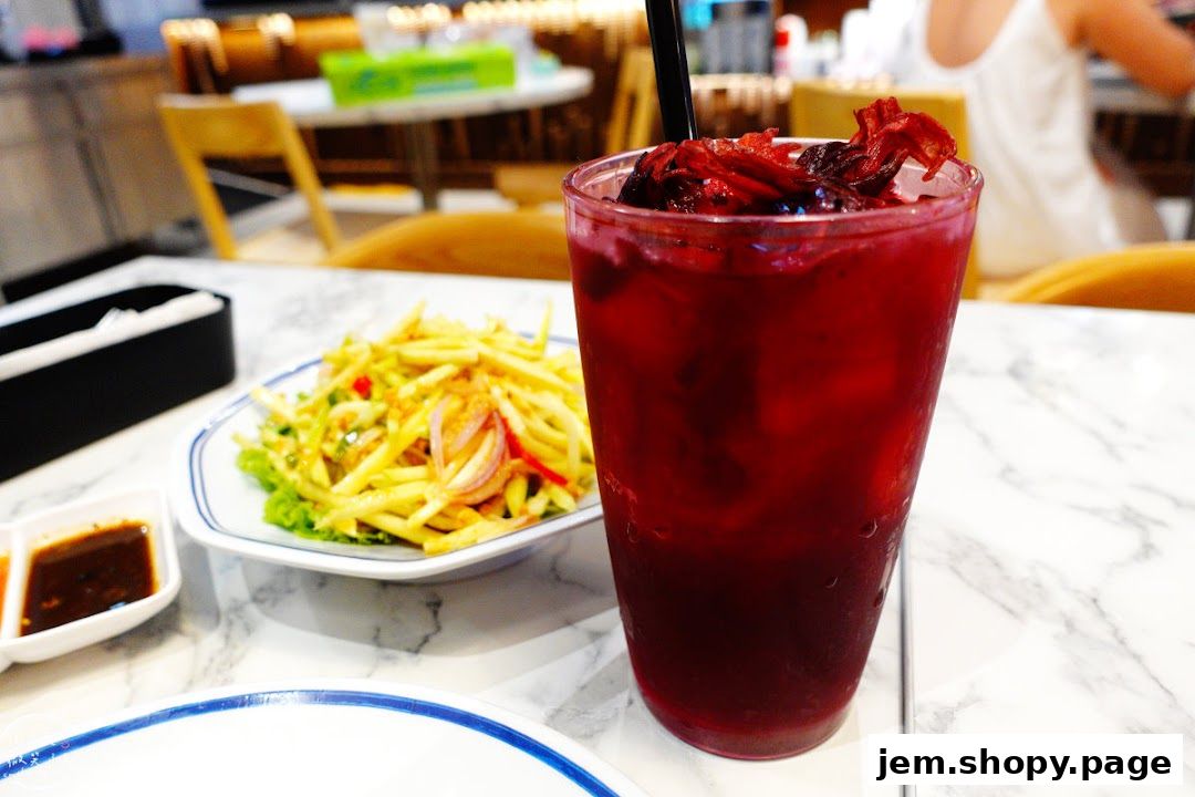 A refreshing red drink and a plate of mango salad on a marble table.