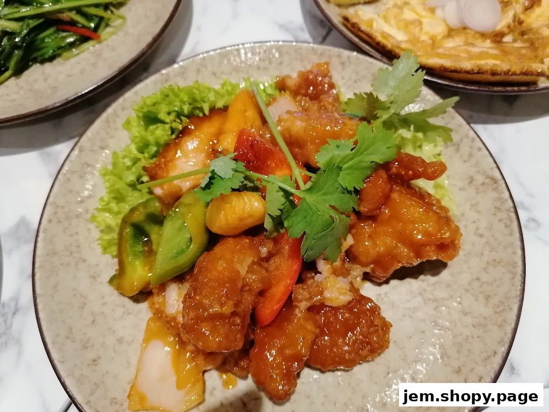 A plate of delicious sweet and sour chicken with vegetables and cilantro garnish.