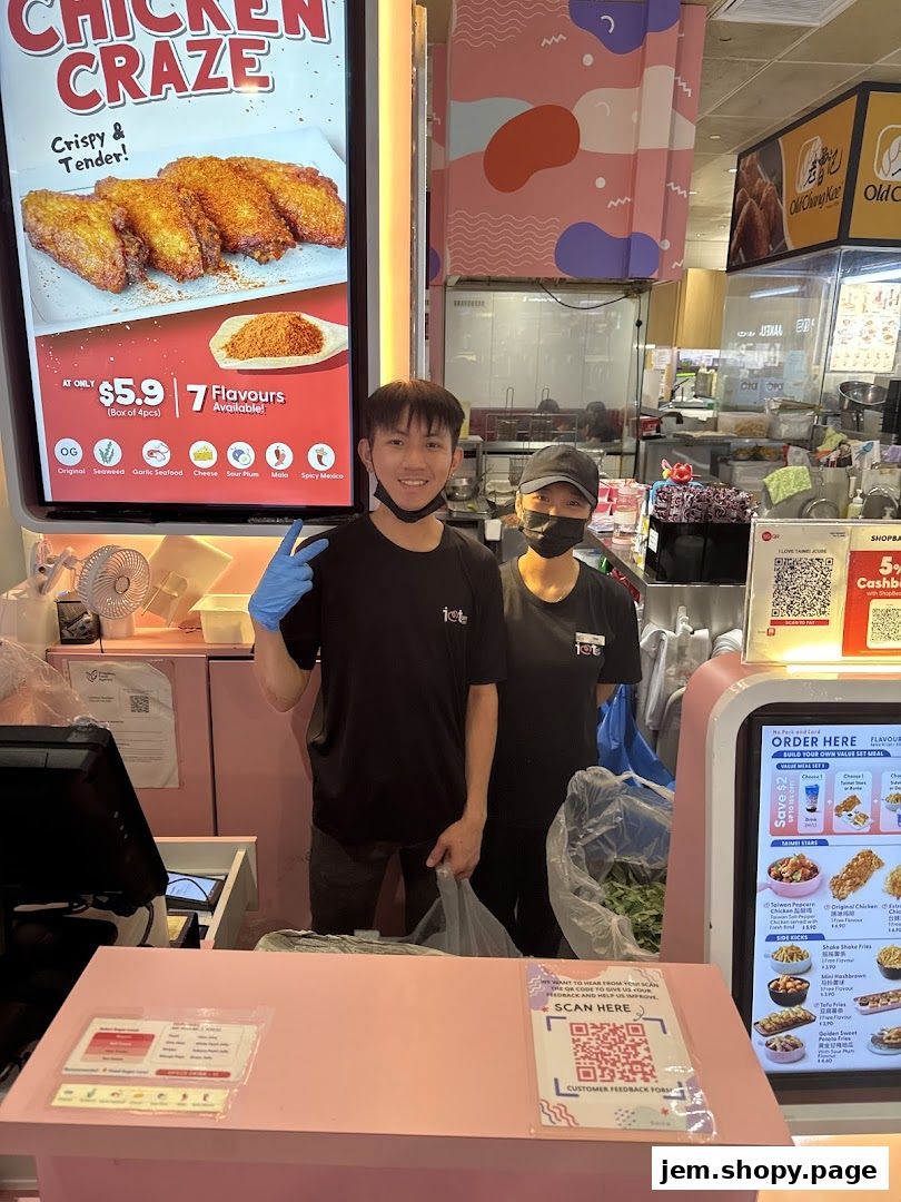 Two staff members stand behind a counter at a fried chicken and bubble tea shop.