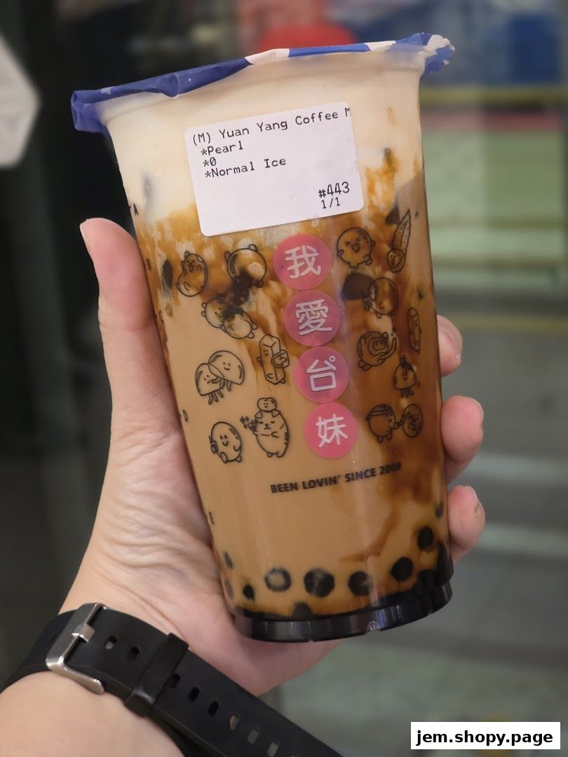 A hand holds a bubble tea with pearls and brown sugar syrup.