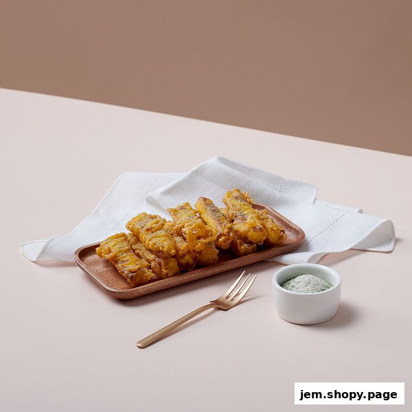 A plate of crispy fried chicken strips served with a side of seasoning and a fork.
