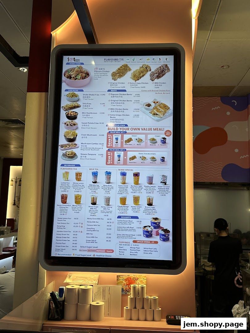 A digital menu board displays a variety of fried chicken, bubble tea, and side dishes with prices.