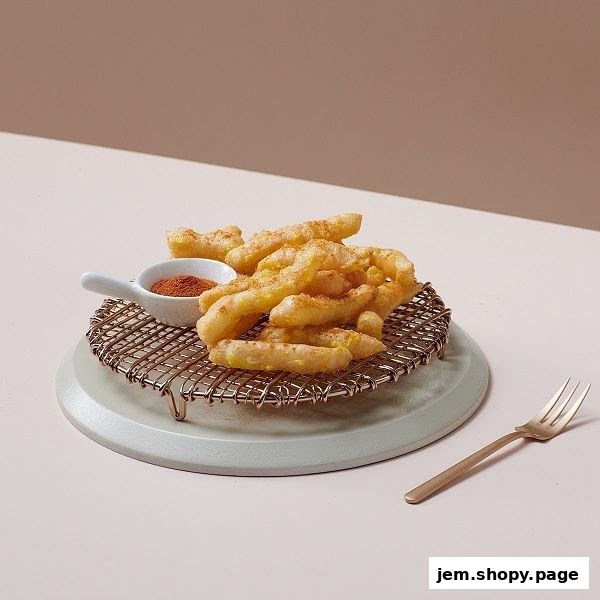 Crispy fried chicken strips served with a side of chili powder on a cooling rack.