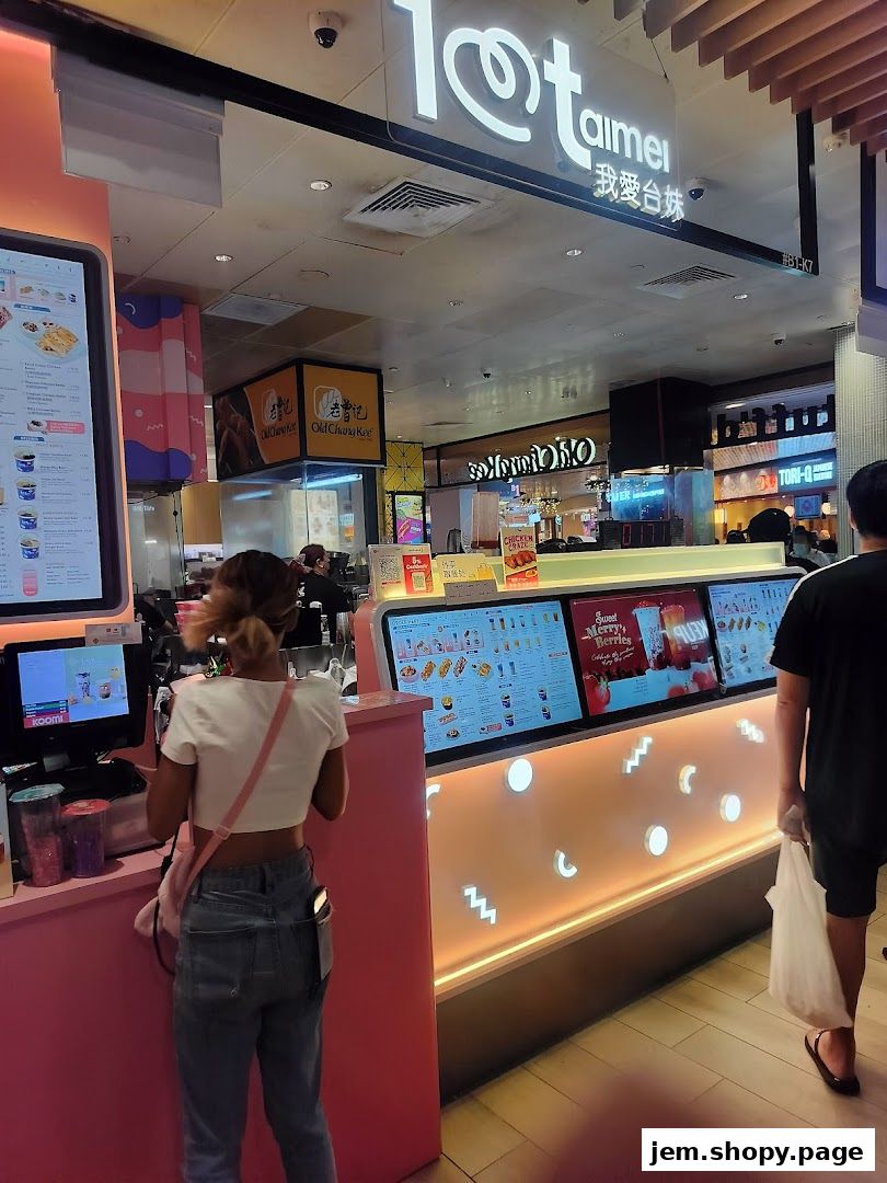 A customer orders at a brightly lit bubble tea and fried chicken shop.