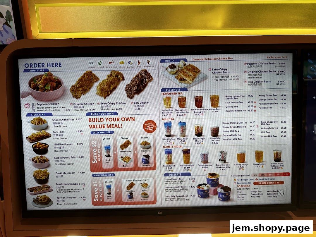 A digital menu board displaying fried chicken, bubble tea, and bento boxes with prices.