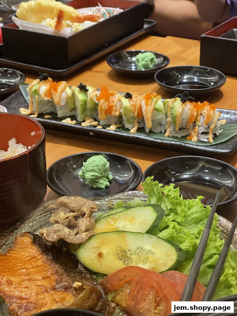 A close-up of a Japanese meal featuring sushi rolls, tempura, and a side salad.