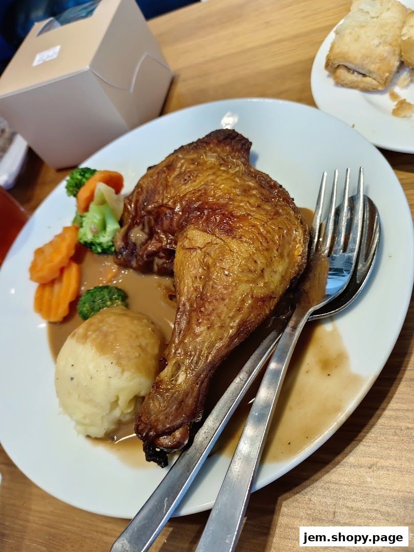 A plate of roasted chicken leg with mashed potatoes and vegetables, served with gravy.