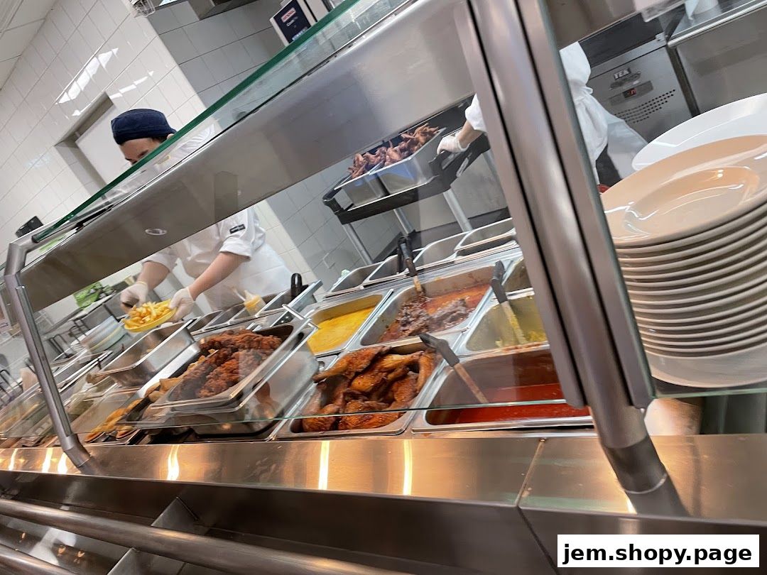 A food service counter with various dishes and a staff member serving fries.