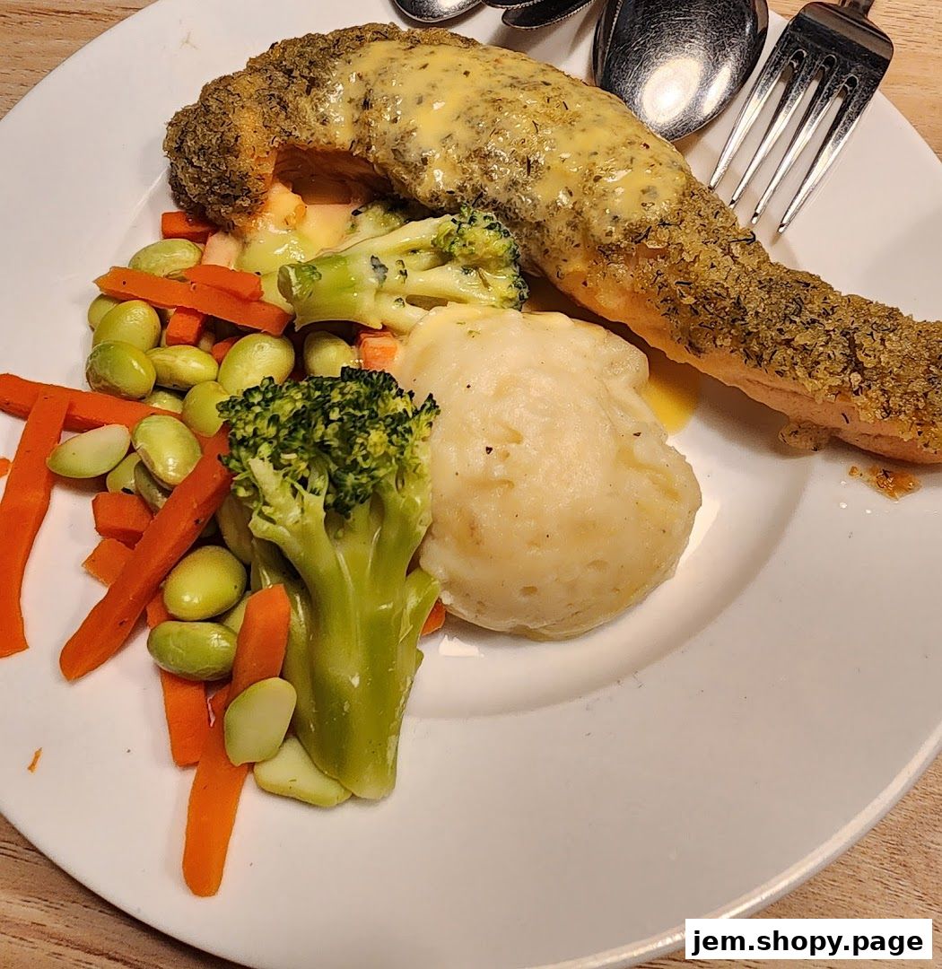 A plate of food with salmon, mashed potatoes, broccoli, carrots, and edamame.
