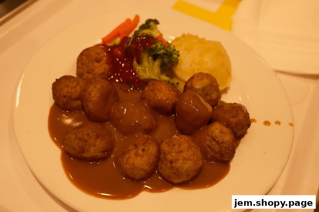 A plate of IKEA meatballs with mashed potatoes, broccoli, carrots, and gravy.
