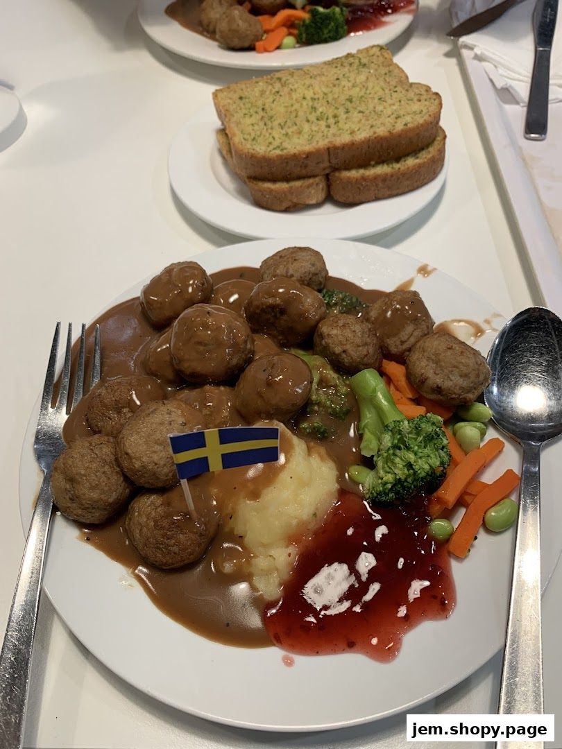 A plate of IKEA meatballs with mashed potatoes, vegetables, and lingonberry jam.